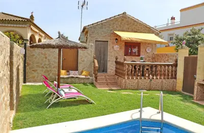 a yard with chairs and an umbrella and a pool at Casa Independiente Conil in Conil de la Frontera