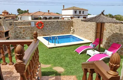 a backyard with a swimming pool and pink chairs at Casa Independiente Conil in Conil de la Frontera