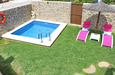 a swimming pool with two chairs and an umbrella at Casa Independiente Conil in Conil de la Frontera