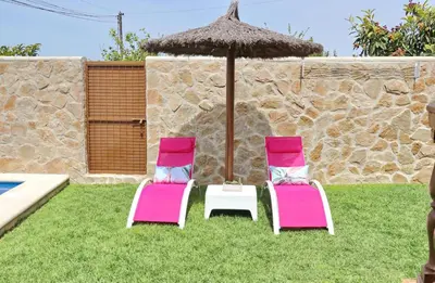 two pink and white chairs and an umbrella at Casa Independiente Conil in Conil de la Frontera