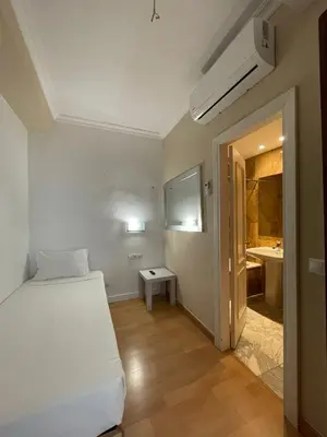 a white bedroom with a bed and a bathroom at Hotel Trafalgar in Jerez de la Frontera