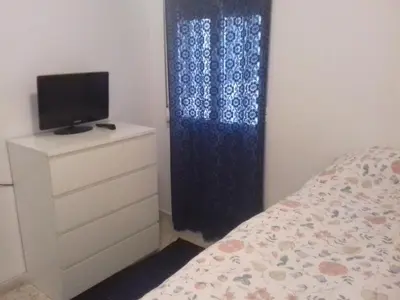 a bedroom with a bed and a tv and a dresser at Apartamento Playa100m in Sanlúcar de Barrameda