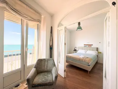 a bedroom with a bed and a chair and the ocean at Balcón al Mar con Ascensor Grupo AC Gestion in Cádiz