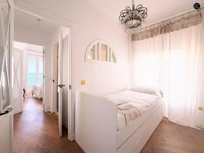a white room with a bed and a chandelier at Balcón al Mar con Ascensor Grupo AC Gestion in Cádiz