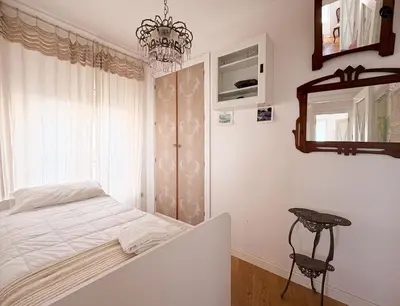 a bedroom with a bed and a chandelier at Balcón al Mar con Ascensor Grupo AC Gestion in Cádiz