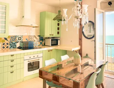 a kitchen with green cabinets and a glass table at Balcón al Mar con Ascensor Grupo AC Gestion in Cádiz