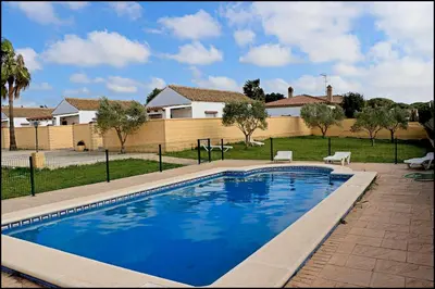a swimming pool in front of a house at Bungalow en complejo I in Conil de la Frontera