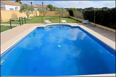 a large blue swimming pool in a yard at Bungalow en complejo I in Conil de la Frontera