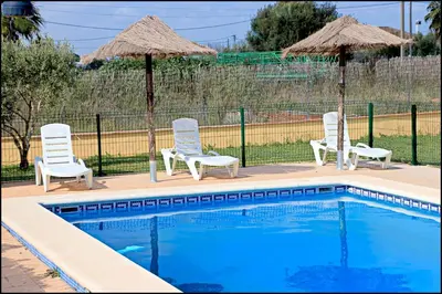 a group of chairs and umbrellas next to a pool at Bungalow en complejo I in Conil de la Frontera