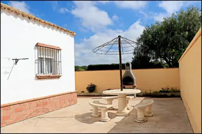 a courtyard with a fountain and a window with an umbrella at Bungalow en complejo I in Conil de la Frontera