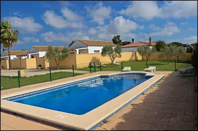 a swimming pool in a yard with a house at Bungalow complejo III in Conil de la Frontera
