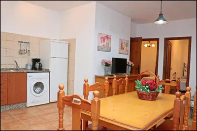 a kitchen and dining room with a wooden table and chairs at Bungalow complejo III in Conil de la Frontera