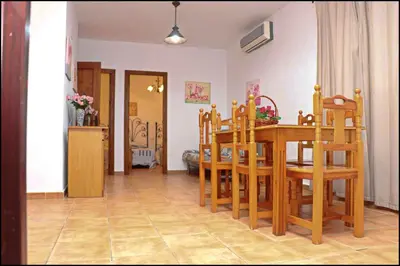 a kitchen and dining room with a wooden table and chairs at Bungalow complejo III in Conil de la Frontera