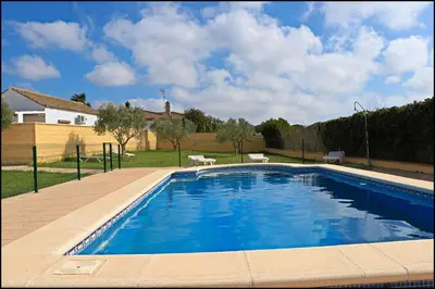 a large blue swimming pool in a yard with a house at Bungalow complejo III in Conil de la Frontera