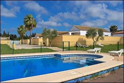 a swimming pool in front of a house at Bungalow complejo III in Conil de la Frontera