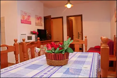 a basket of red flowers sitting on a table at Bungalow en complejo II in Conil de la Frontera