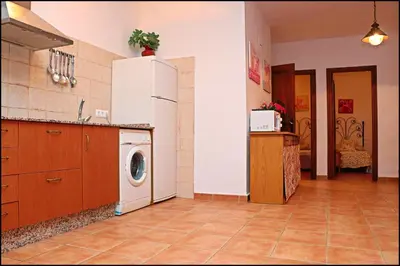 a kitchen with a refrigerator and a washing machine at Bungalow en complejo II in Conil de la Frontera