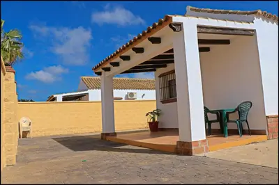 a gazebo with a green chair on a patio at Bungalow en complejo II in Conil de la Frontera