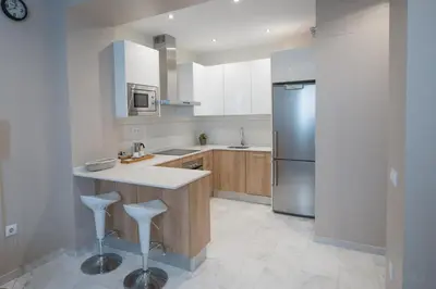 a kitchen with a stainless steel refrigerator and stools at Sagasta 13 in Cádiz