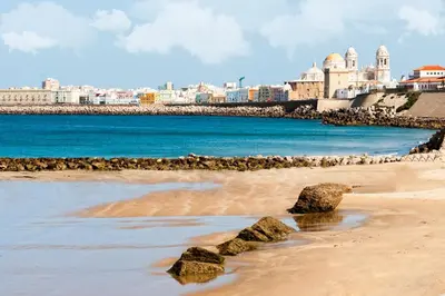 a beach with rocks and buildings in the background at Sagasta 13 in Cádiz