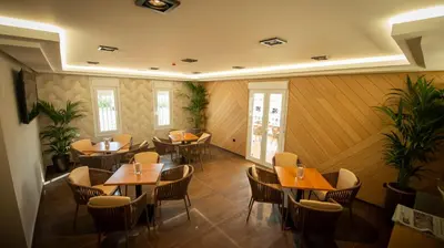 a restaurant with wooden tables and chairs and plants at Hotel y Apartamentos Diufain in Conil de la Frontera