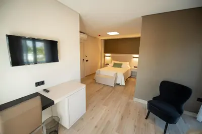 a room with a bedroom with a bed and a chair at Hotel y Apartamentos Diufain in Conil de la Frontera