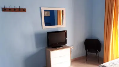 a bedroom with a television on a dresser with a chair at Hostal Manolo in El Puerto de Santa María