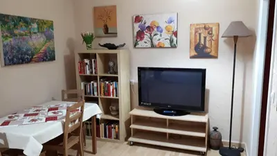 a living room with a tv and a table and a dining room at Hostal Manolo in El Puerto de Santa María