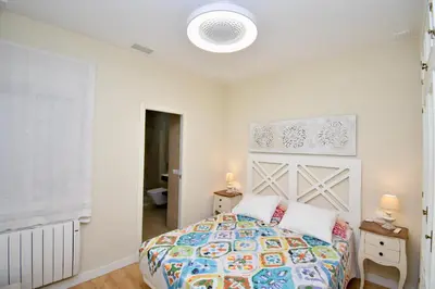 a white bedroom with a bed with a colorful comforter at El Patio in Cádiz