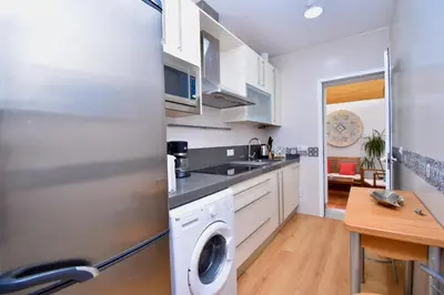a kitchen with white cabinets and a washer and dryer at El Patio in Cádiz