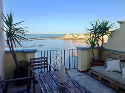 a balcony with a couch and a view of the beach at Ático Playa Muralla in El Puerto de Santa María