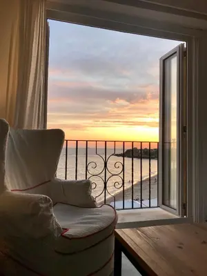 a living room with a chair and a view of the ocean at Ático Playa Muralla in El Puerto de Santa María