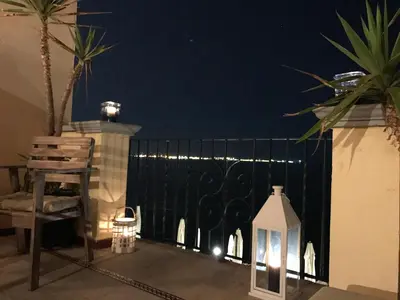 a balcony with a gate at night with lights at Ático Playa Muralla in El Puerto de Santa María