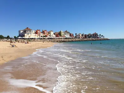 a beach with a group of people in the water at Ático Playa Muralla in El Puerto de Santa María