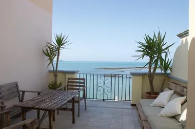 a balcony with a table and chairs and the ocean at Ático Playa Muralla in El Puerto de Santa María
