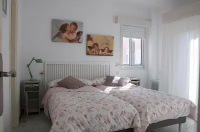 a bedroom with a bed and two pictures on the wall at Ático Playa Muralla in El Puerto de Santa María