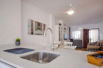 a kitchen with a sink and a living room at Real de La Barrosa 46 in Chiclana de la Frontera