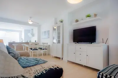 a living room with a couch and a television on a cabinet at Real de La Barrosa 46 in Chiclana de la Frontera
