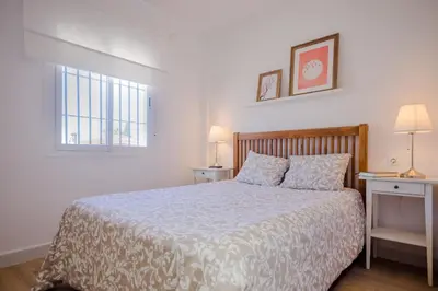a bedroom with a bed and two tables and a window at Real de La Barrosa 46 in Chiclana de la Frontera
