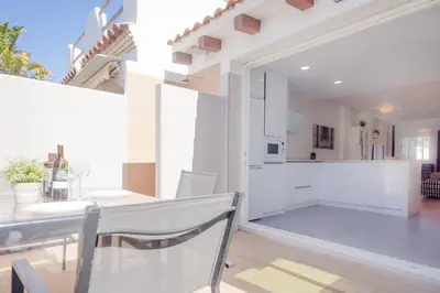 a kitchen and dining room with a table and chairs at Real de La Barrosa 46 in Chiclana de la Frontera