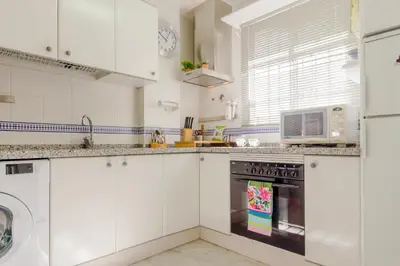 a kitchen with white cabinets and a microwave at Duplex El Manantial in El Puerto de Santa María