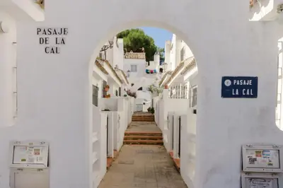 an alley with white buildings and an archway at Duplex El Manantial in El Puerto de Santa María