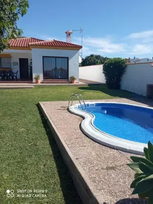 a swimming pool in a yard next to a house at Chalet Las Adelfas Chaparrillo in Conil de la Frontera