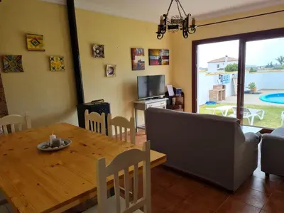 a living room with a wooden table and a couch at Chalet Las Adelfas Chaparrillo in Conil de la Frontera