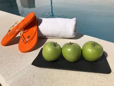 three apples on a black cutting board next to a scissors at Alojamiento Rural La Mejora in Conil de la Frontera