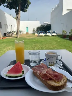 a black tray with a sandwich and a cup of orange juice at Alojamiento Rural La Mejora in Conil de la Frontera