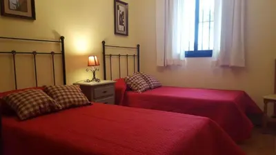 two beds in a bedroom with red sheets and a window at Chalet Roche - Pilahito in Conil de la Frontera