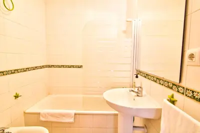 a white bathroom with a tub and a sink at Apartamentos Centro 1 El Puerto de Santa Maria in El Puerto de Santa María
