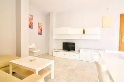 a white living room with a table and a tv at Apartamentos Centro 1 El Puerto de Santa Maria in El Puerto de Santa María