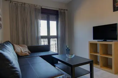 a living room with a couch and a tv and a table at Apartamentos Centro 1 El Puerto de Santa Maria in El Puerto de Santa María